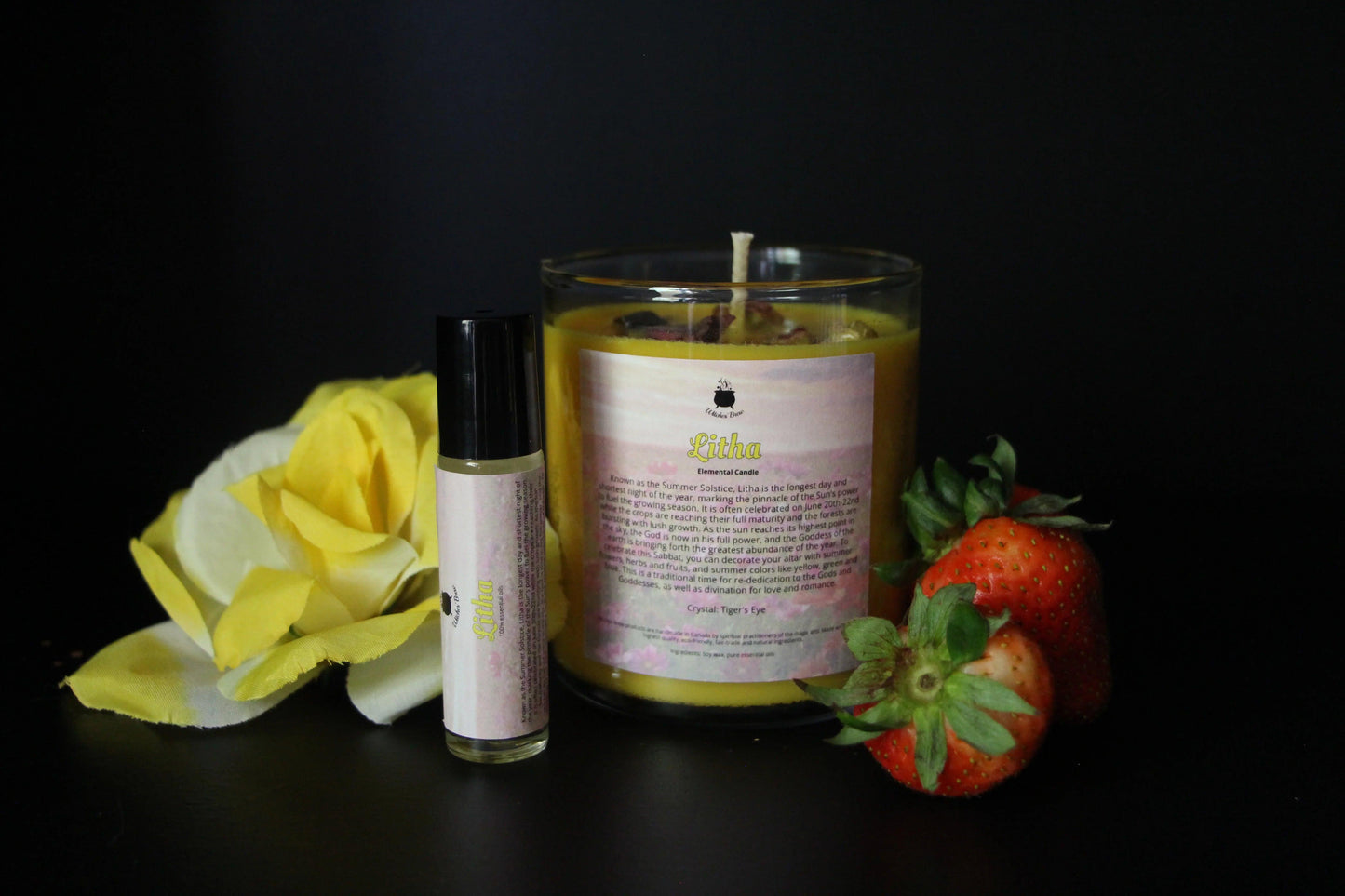 Litha ritual candle and essential oil with yellow rose and fresh strawberries on black background