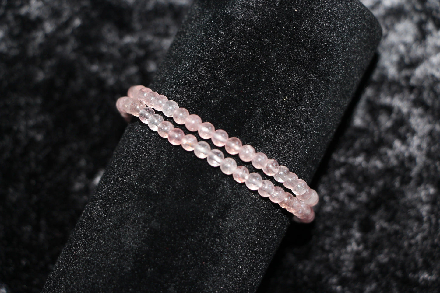 Rose quartz crystal bead bracelets displayed on black velvet