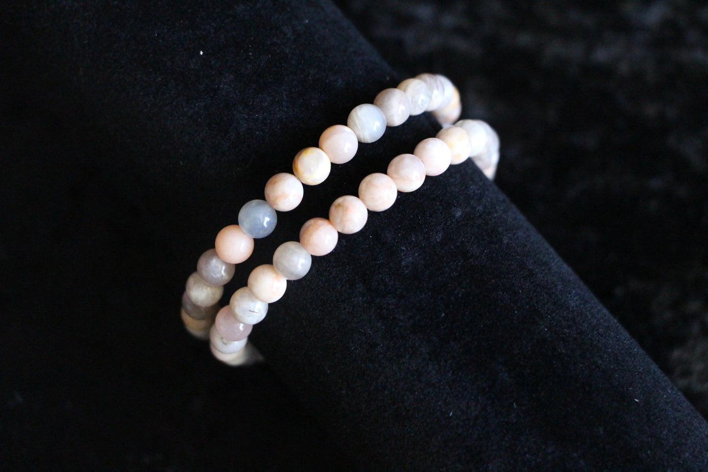 Natural gemstone bead bracelets with pastel hues on black velvet background