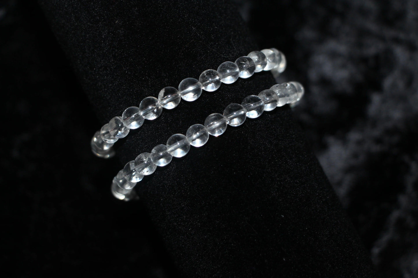Clear quartz crystal bead bracelets on black velvet background