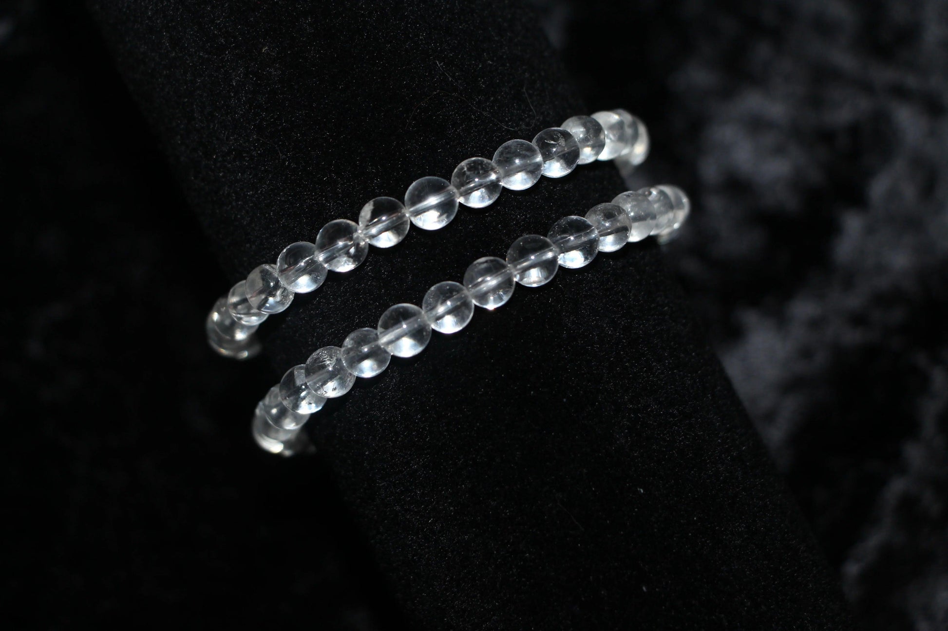 Clear quartz crystal bead bracelets on black velvet background