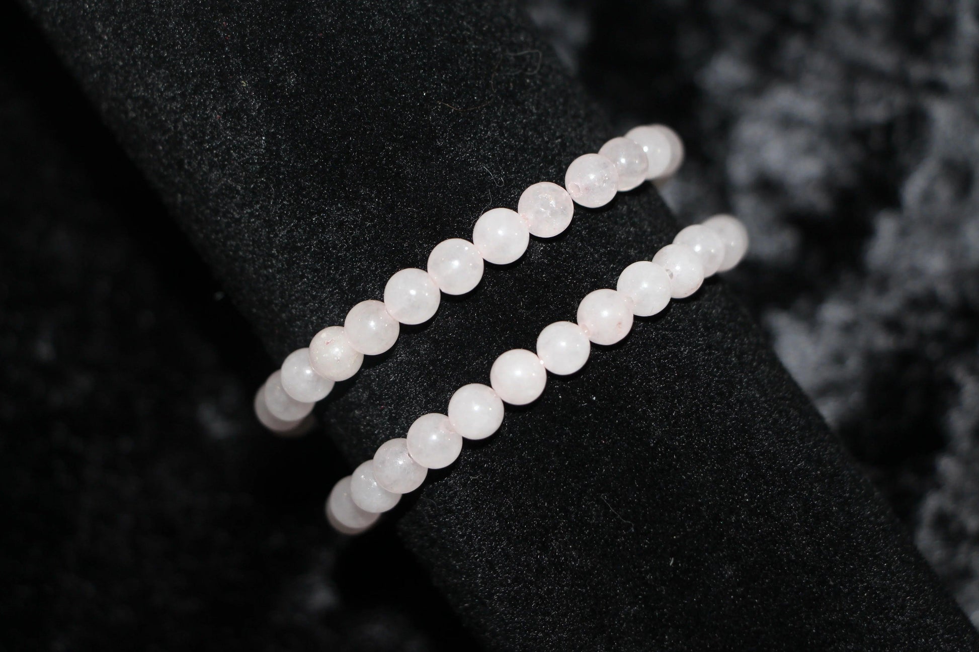Rose quartz crystal bead bracelets on black velvet background