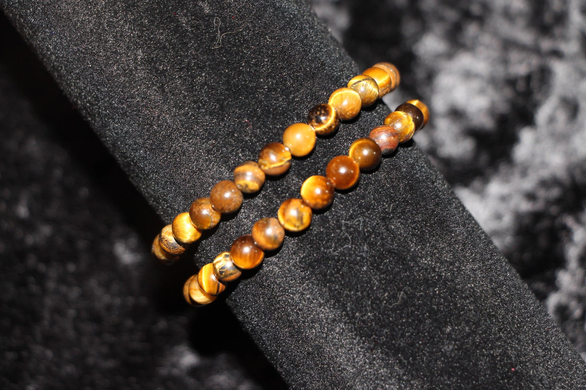 Tiger’s eye crystal bead bracelets on black velvet, gemstone jewelry for rituals