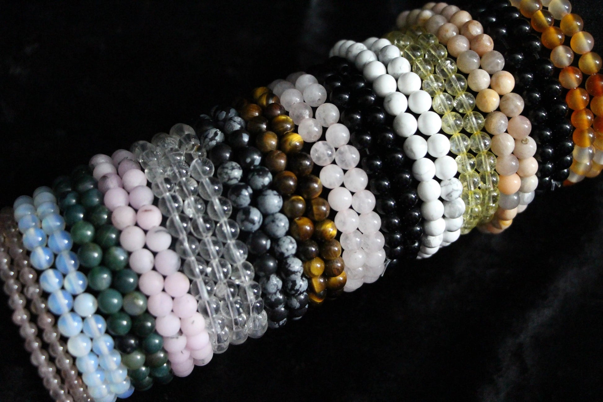 Assorted crystal beaded bracelets in various colors on black background
