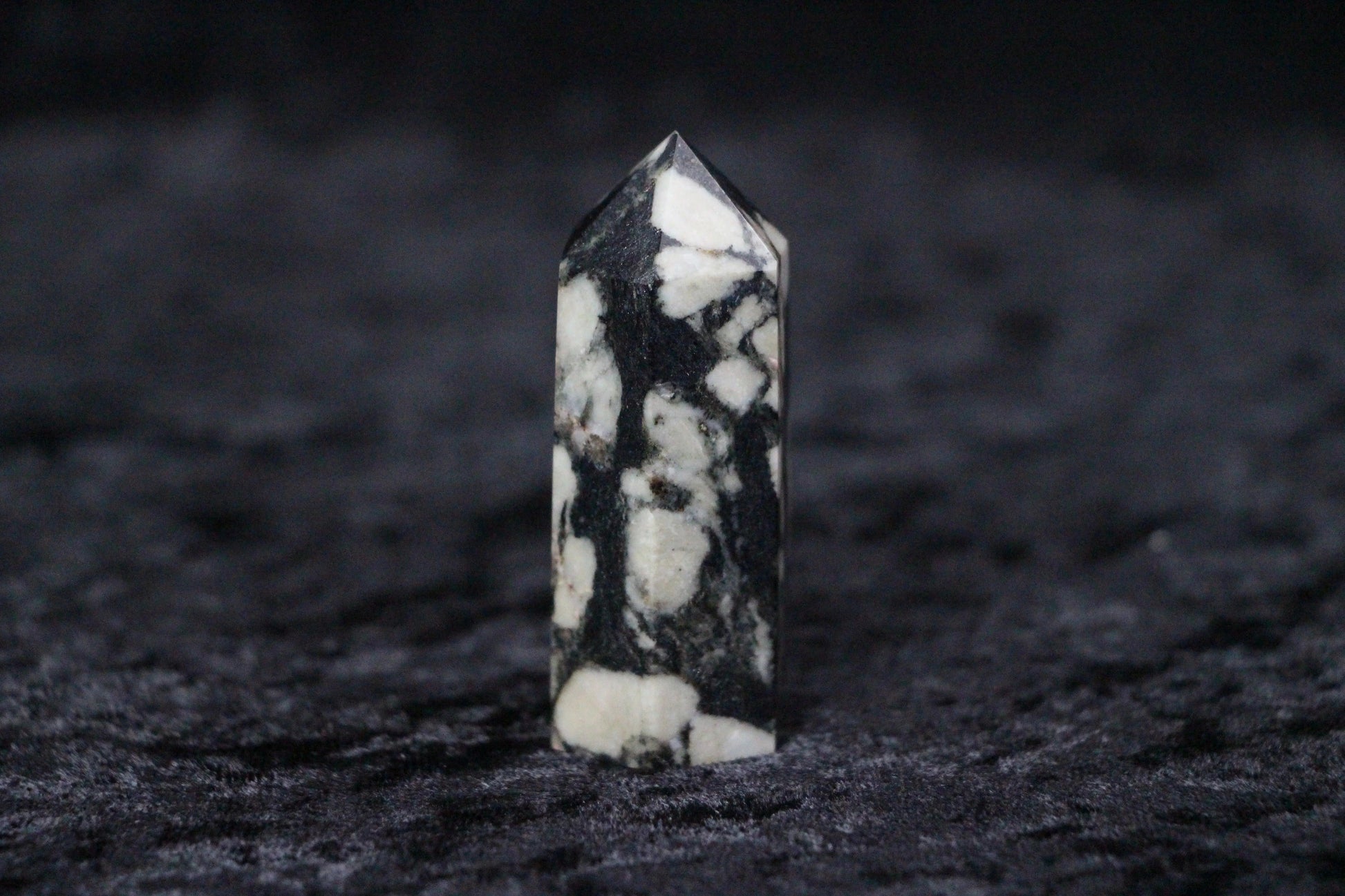 Black and white patterned crystal tower standing on a textured dark surface