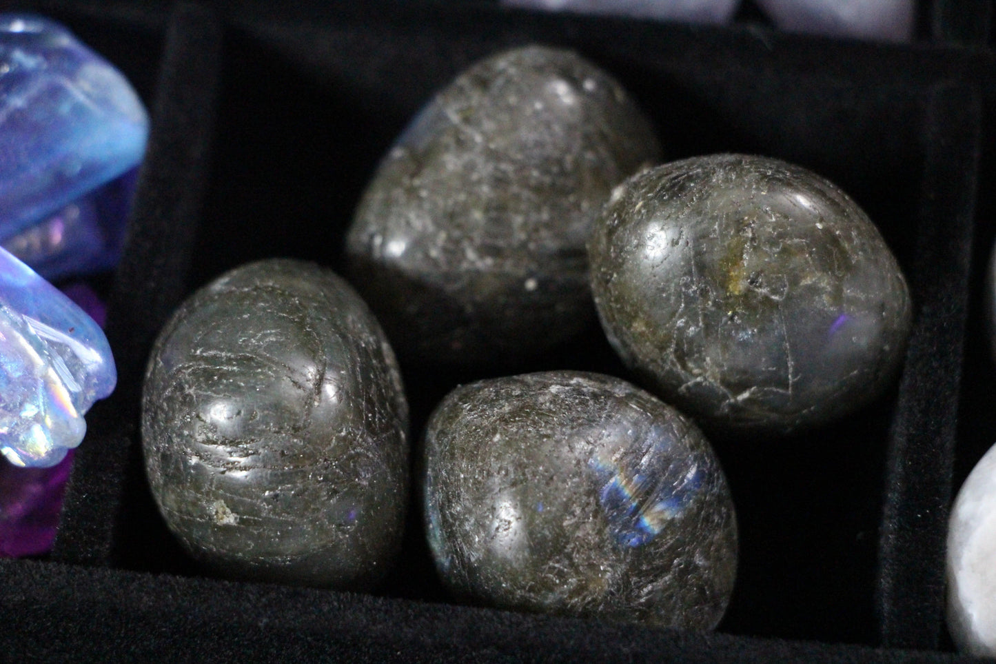 Polished labradorite tumbled stones in a black velvet tray for modern witch rituals