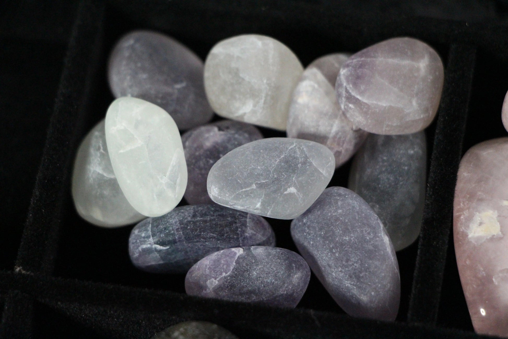 Polished amethyst and quartz crystals in a black velvet tray for modern witch rituals