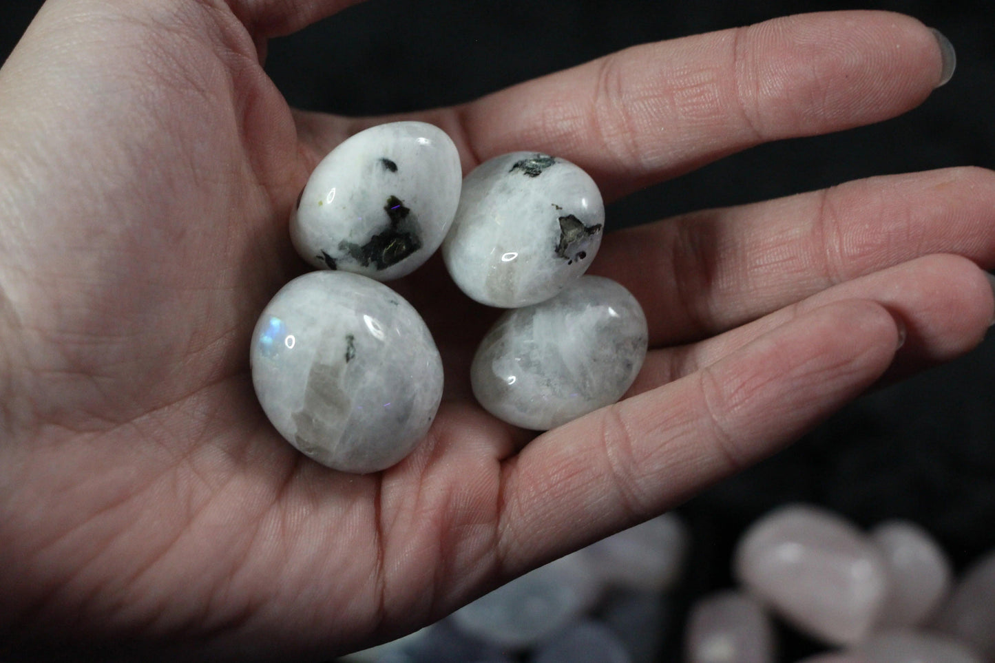 Hand holding four polished moonstone crystals, Witches' Brew ritual tools