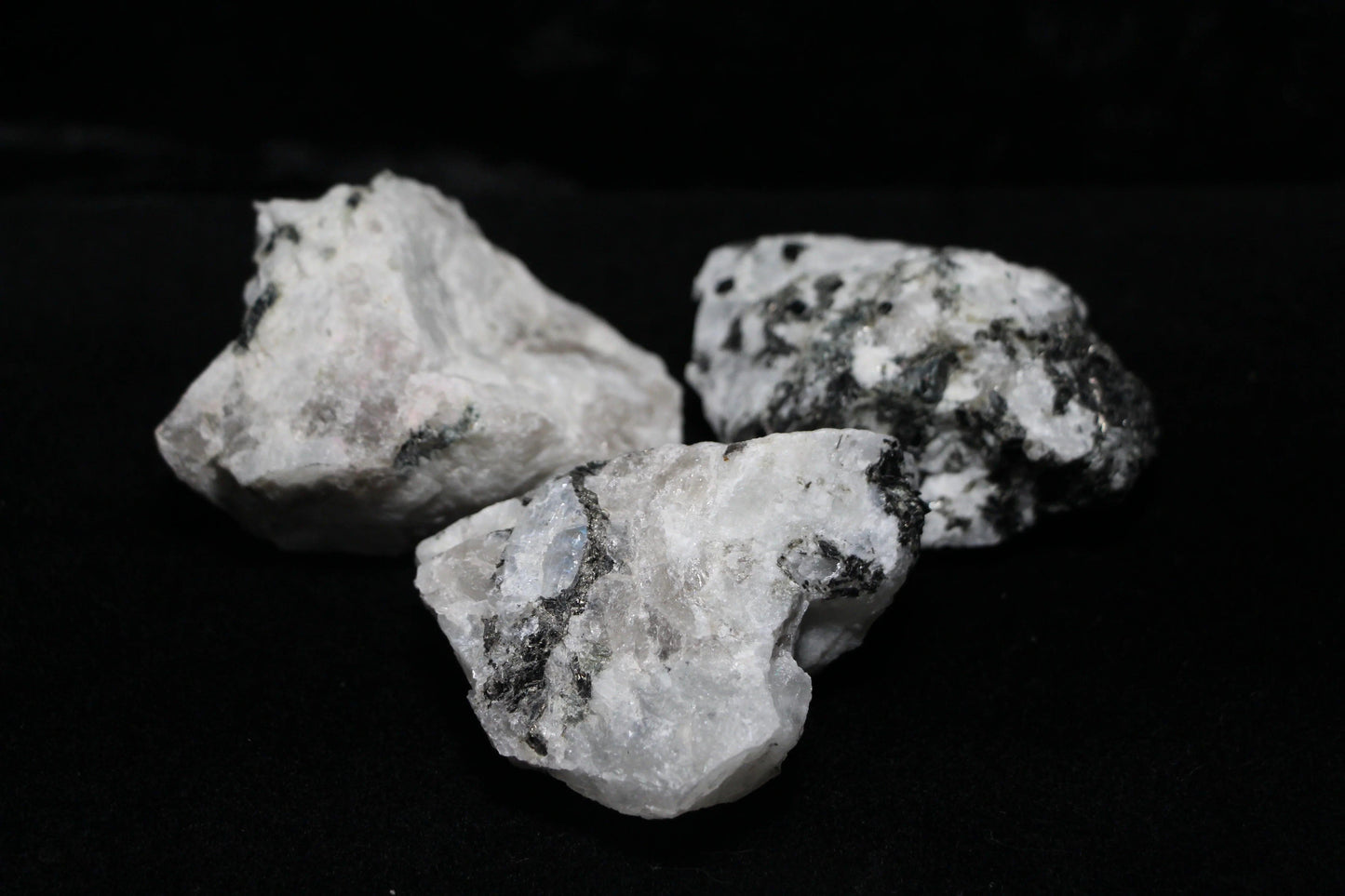 Raw moonstone crystals with black inclusions on black background, Witches' Brew ritual tools