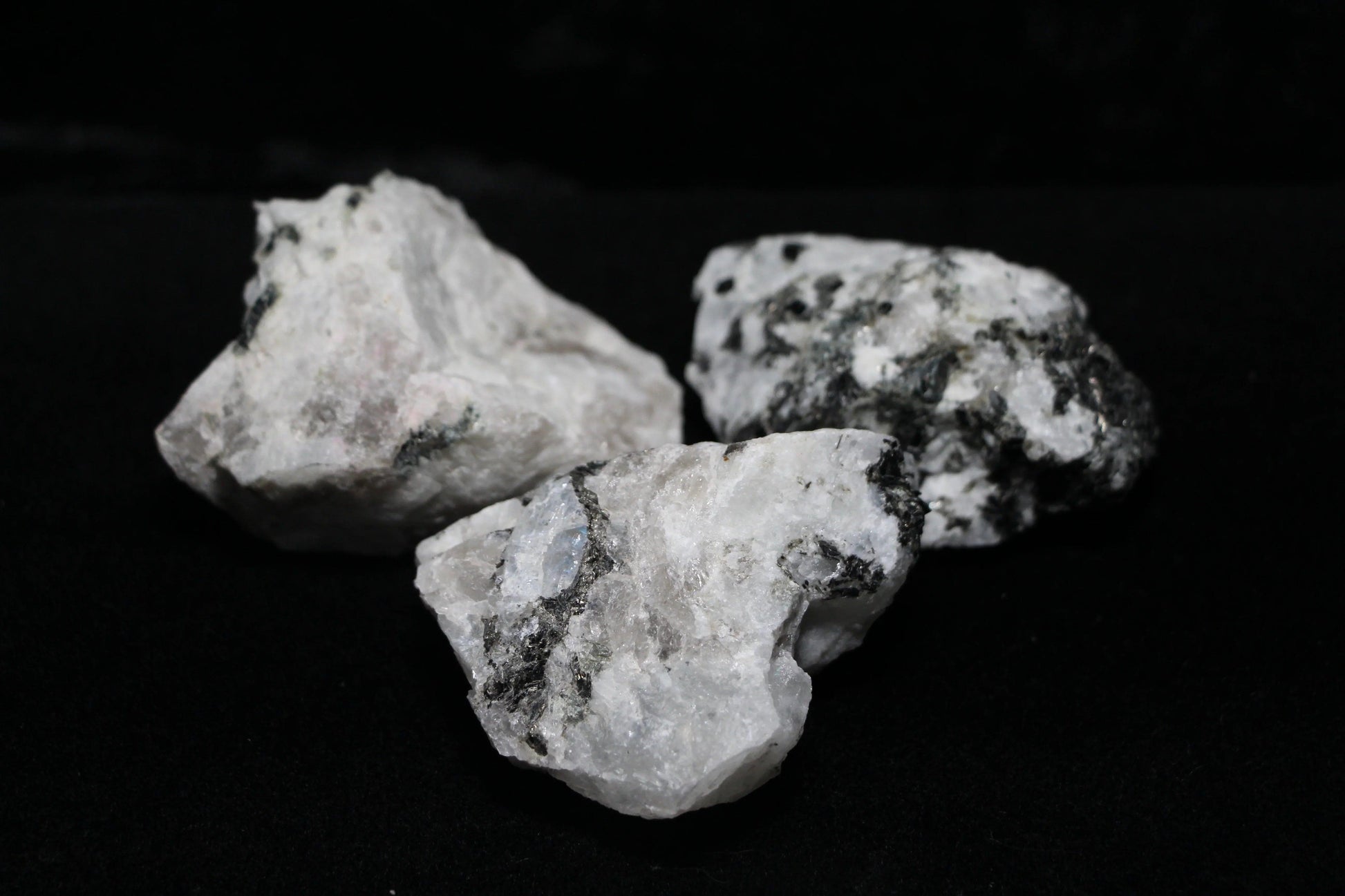 Raw moonstone crystals with black inclusions on black background, Witches' Brew ritual tools