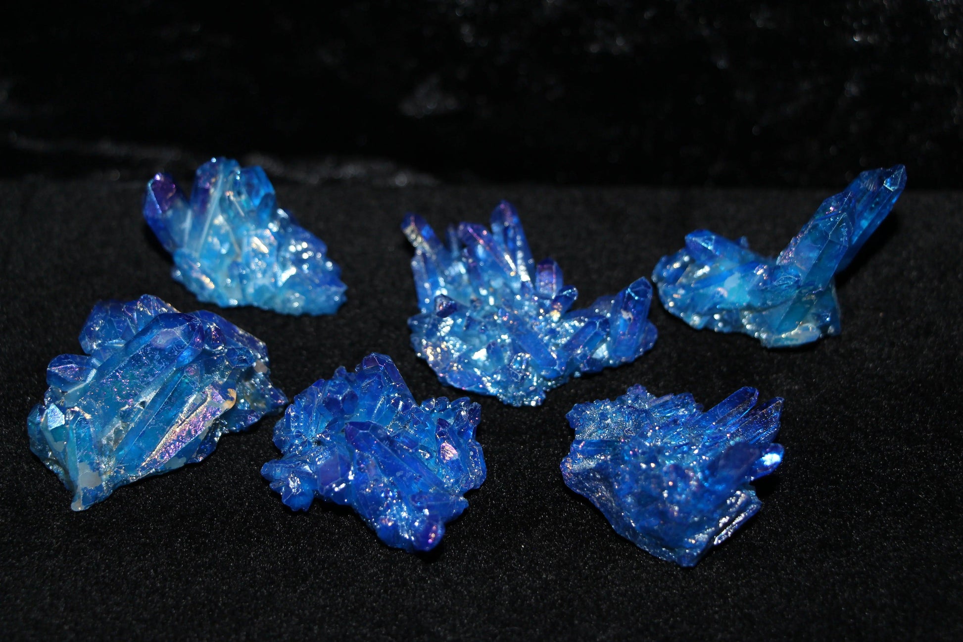 Iridescent blue crystal clusters on a black velvet background, ritual stone decor
