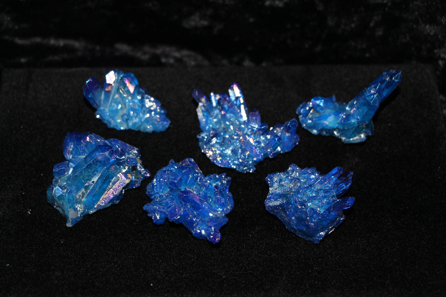 Blue iridescent crystal clusters displayed on black velvet for modern witch ritual decor