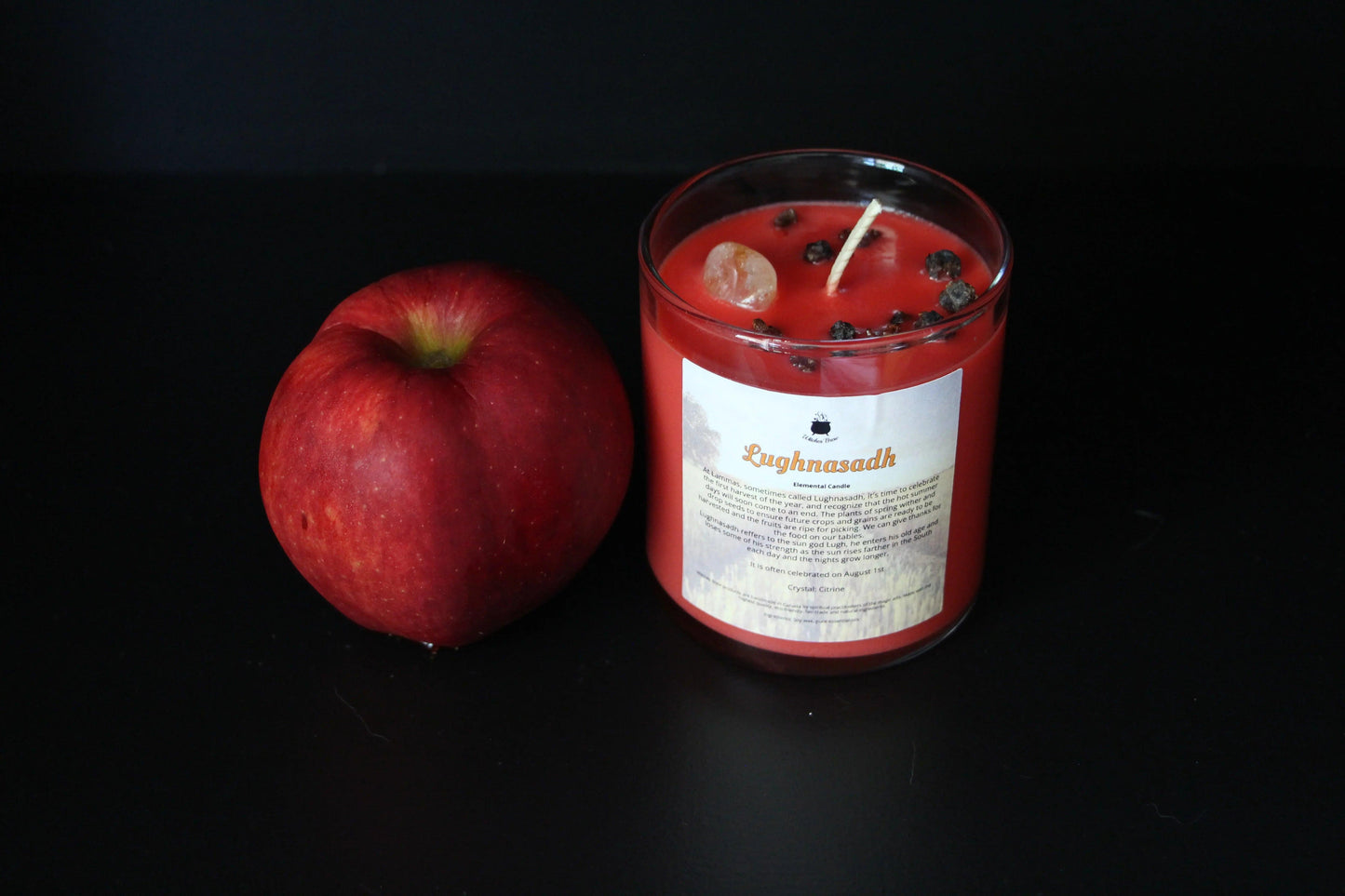 Red apple and Lughnasadh crystal candle on black background, Witches' Brew sustainable handmade decor
