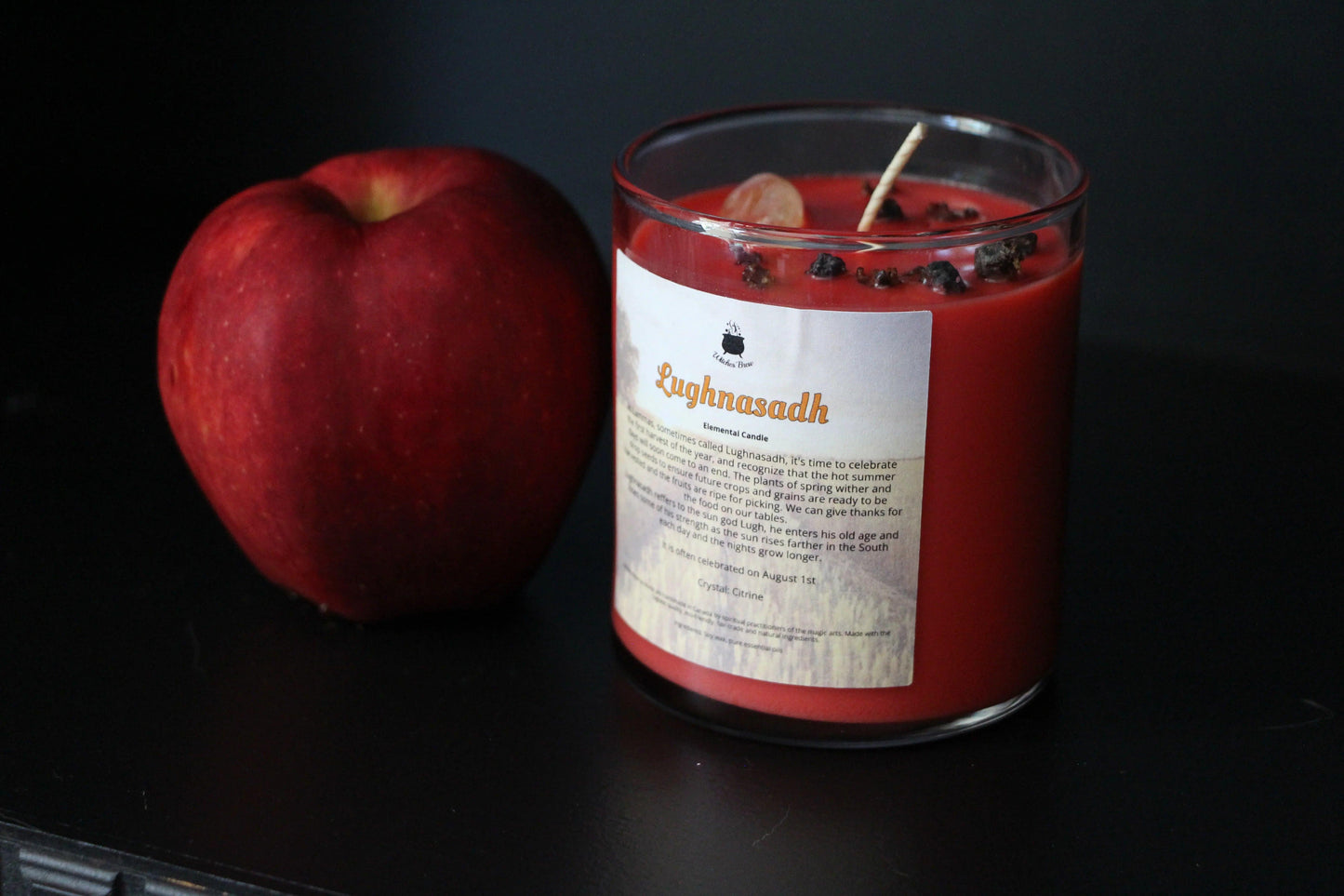 Red apple and Lughnasadh crystal candle on black background, Witches' Brew hand-crafted goods