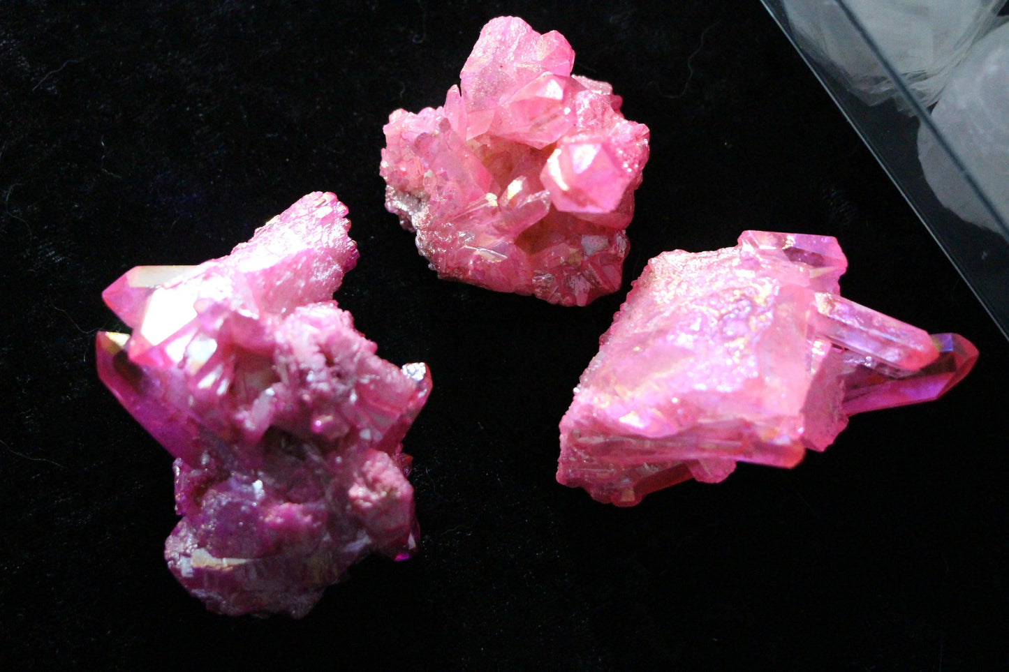 Three bright pink crystal clusters on a black surface, modern witch ritual decor