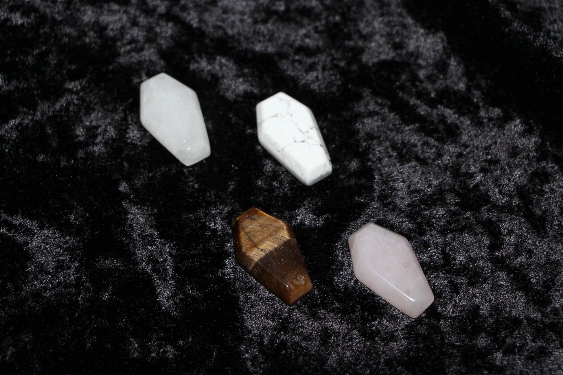 Assorted coffin-shaped crystal stones on black velvet for modern witch rituals