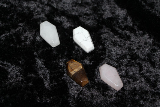 Assorted coffin-shaped crystal stones on black velvet for modern witch rituals