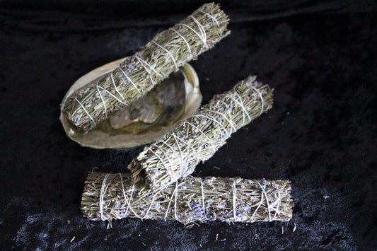 Hand-crafted sage bundles and abalone shell on black cloth, ritual tools for modern witches.