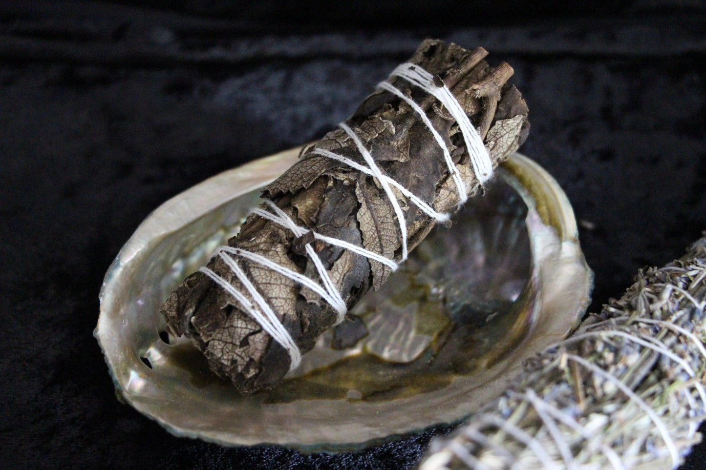 Hand-tied herb smudge bundle on abalone shell for ritual cleansing