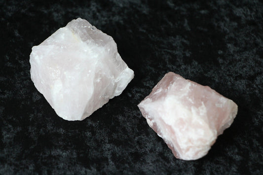 Two raw rose quartz crystals on a black velvet surface, modern witch crystal decor