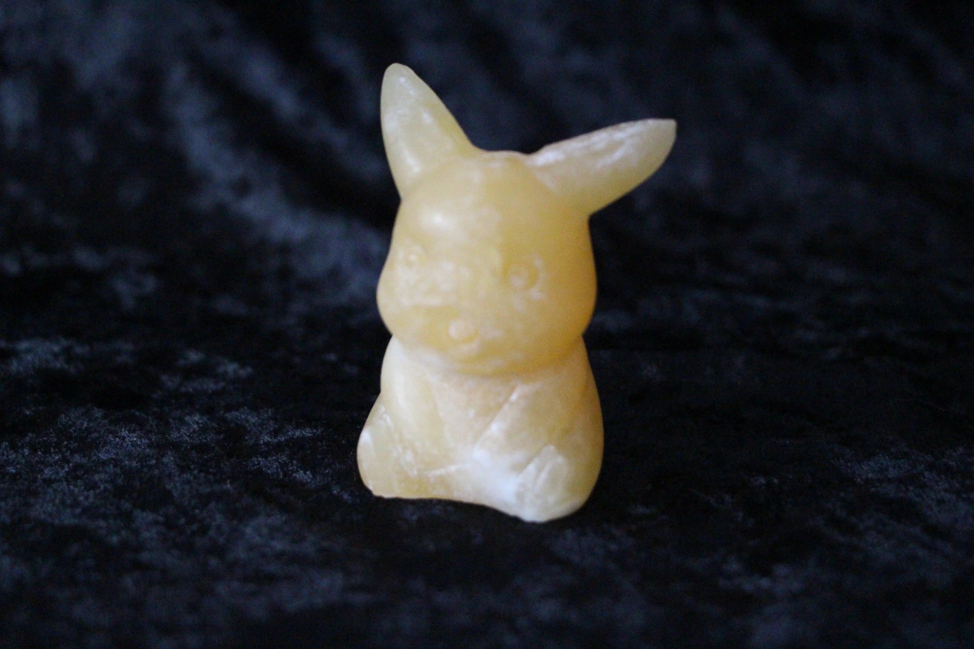 Hand-crafted yellow crystal bunny figure on black velvet, modern witch ritual decor.