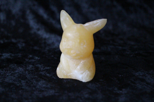 Hand-crafted yellow crystal bunny figure on black velvet, modern witch ritual decor.