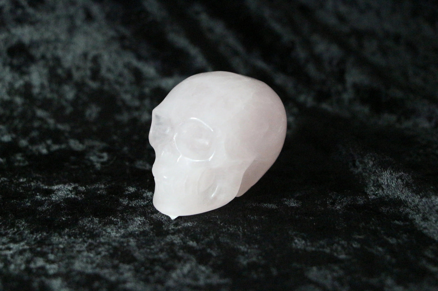Rose quartz crystal skull on black velvet background, ritual and spiritual decor