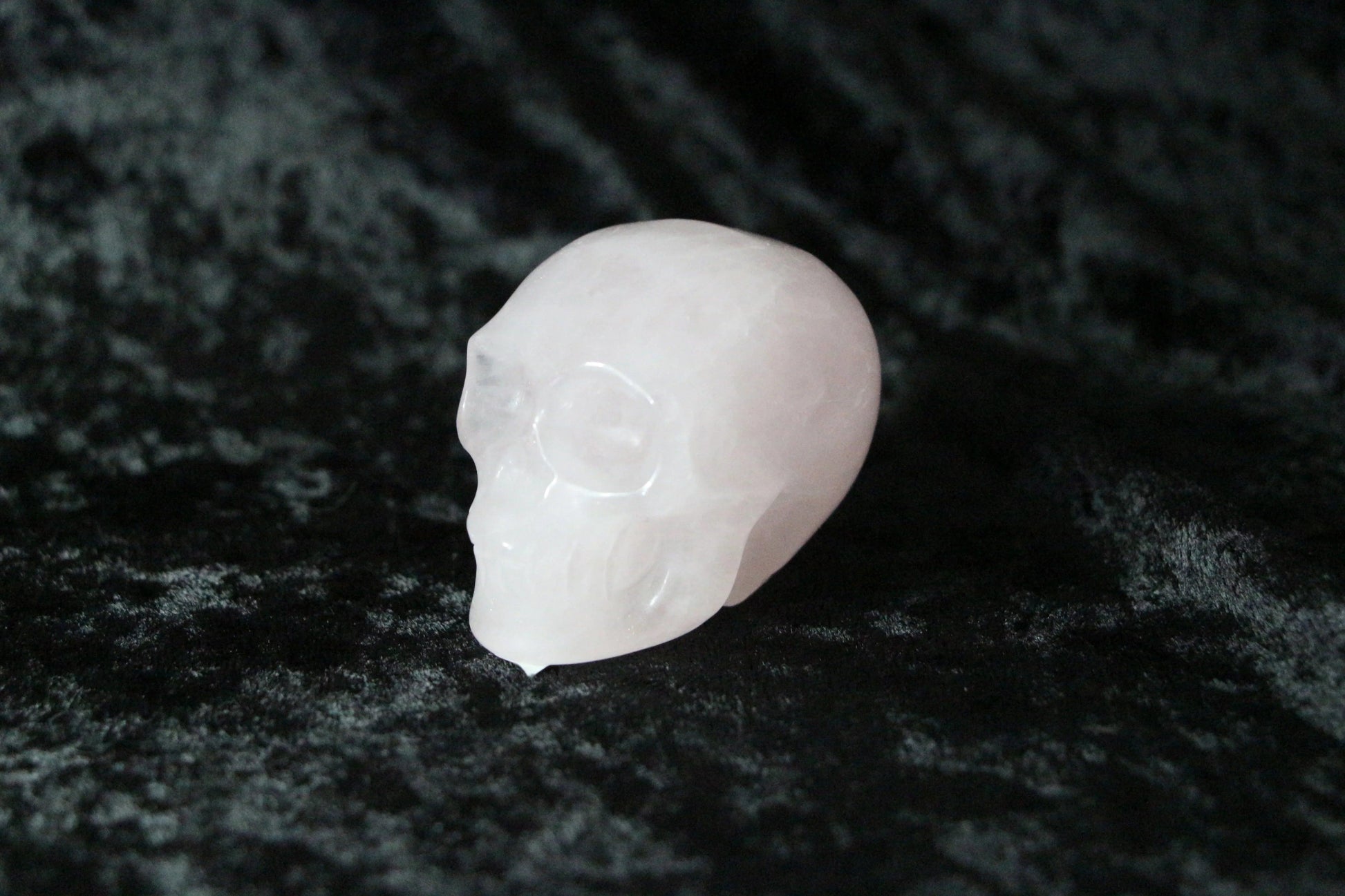 Rose quartz crystal skull on black velvet background, ritual and spiritual decor