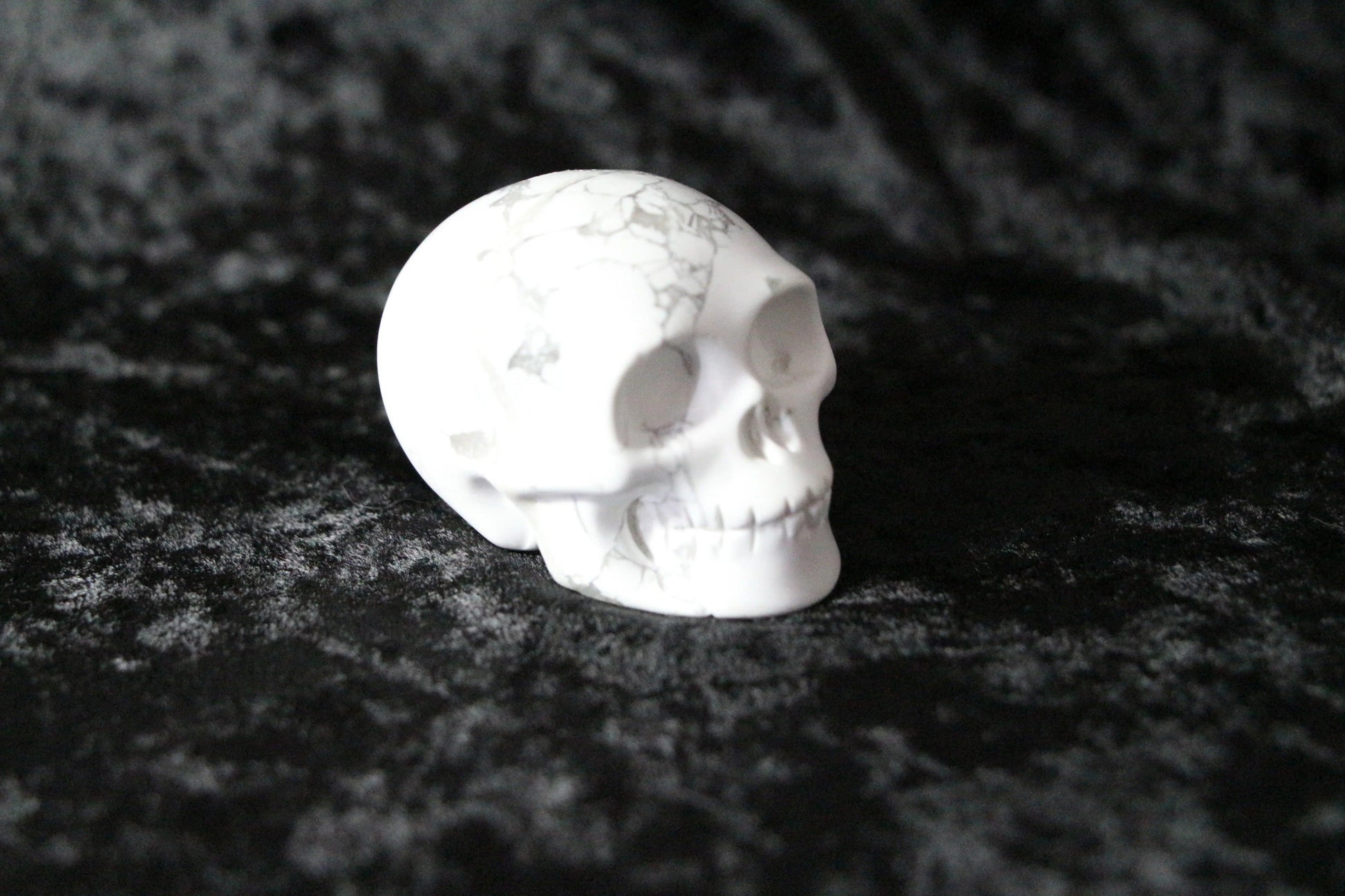 White howlite crystal skull on black velvet background, ritual decor
