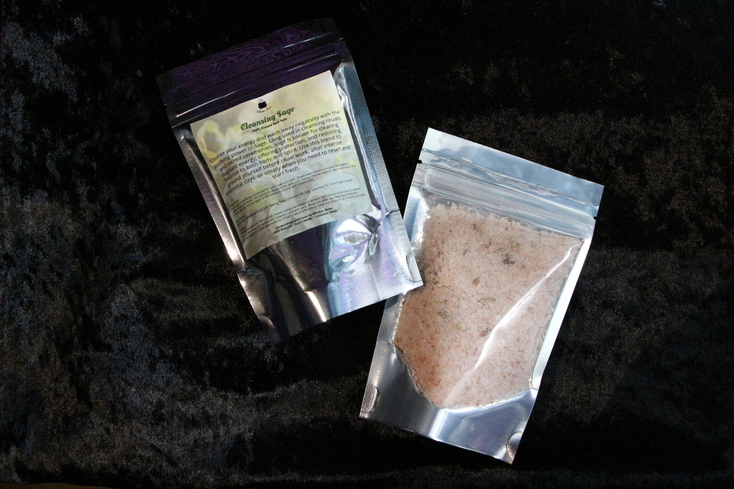 Two resealable pouches of cleansing sage bath salts on a black velvet surface