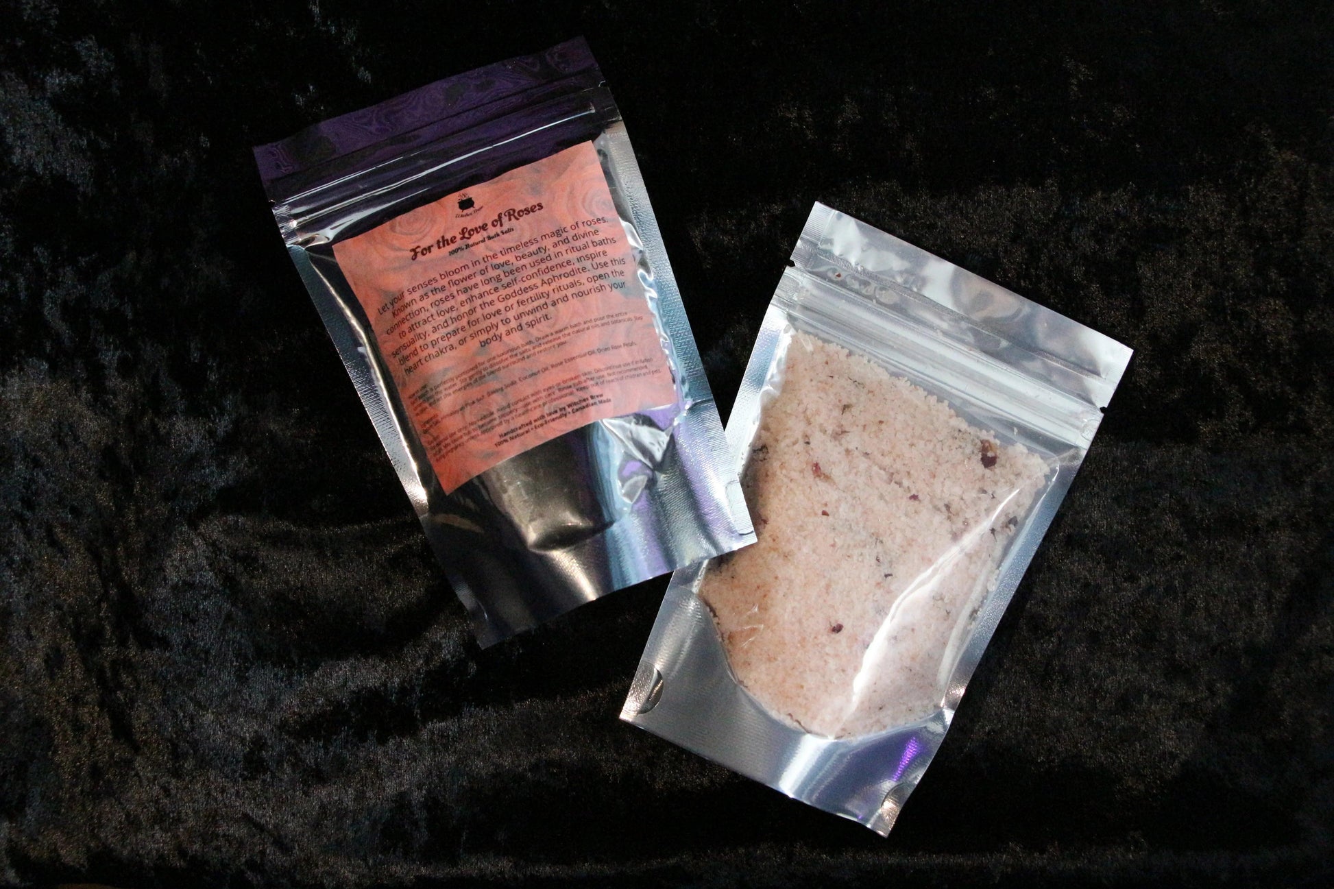 Two silver resealable pouches of bath salts on black fabric, one labeled 'For the Love of Roses'
