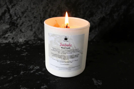 Handmade Imbolc ritual candle burning on a dark textured surface