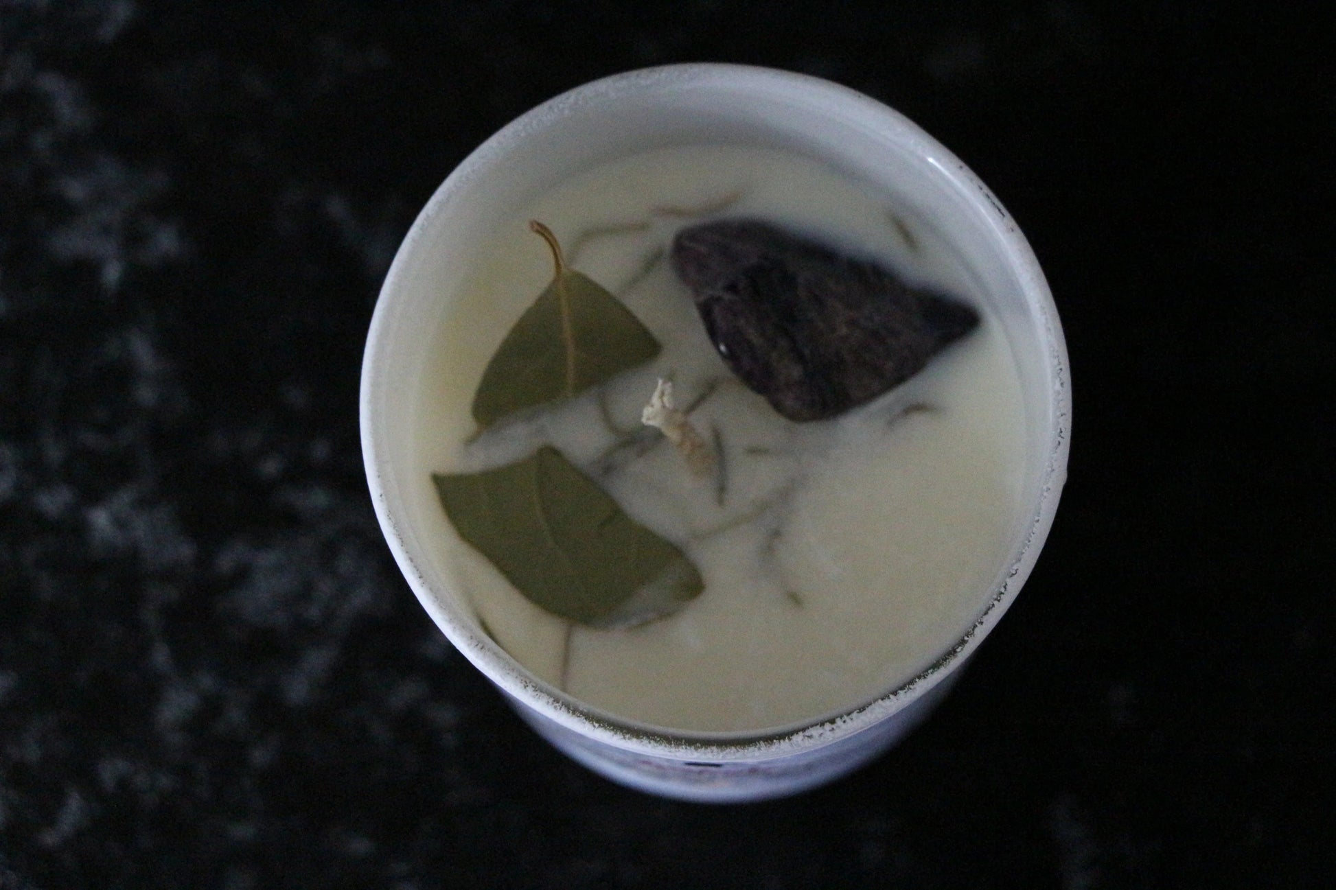 Hand-crafted crystal candle with bay leaves and amethyst on white wax for ritual use