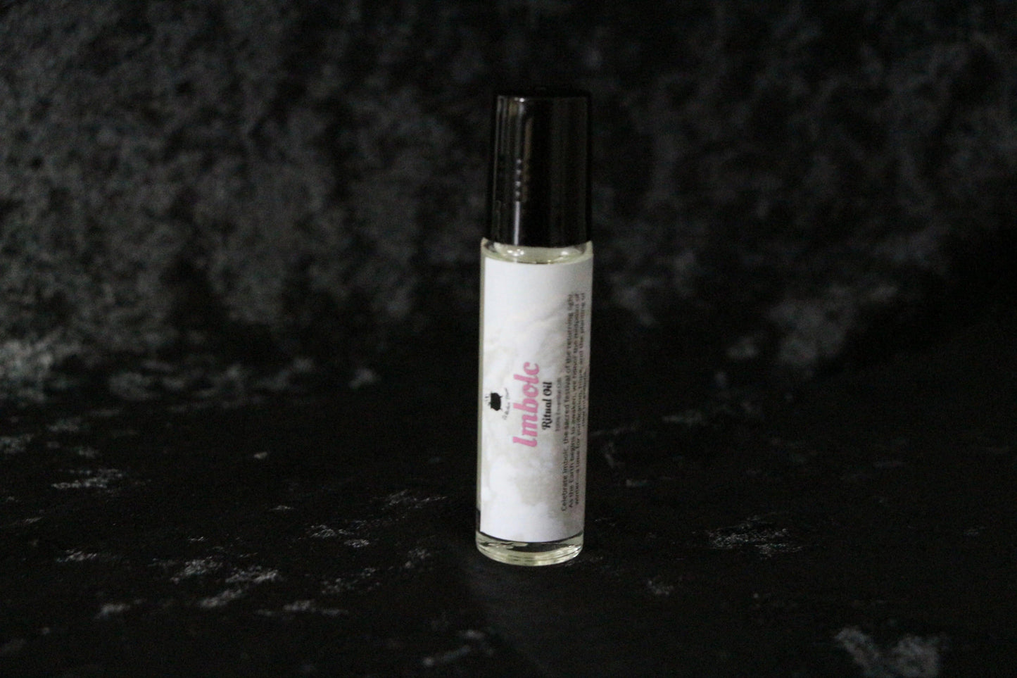 Imbolc ritual oil bottle with black cap on textured dark background