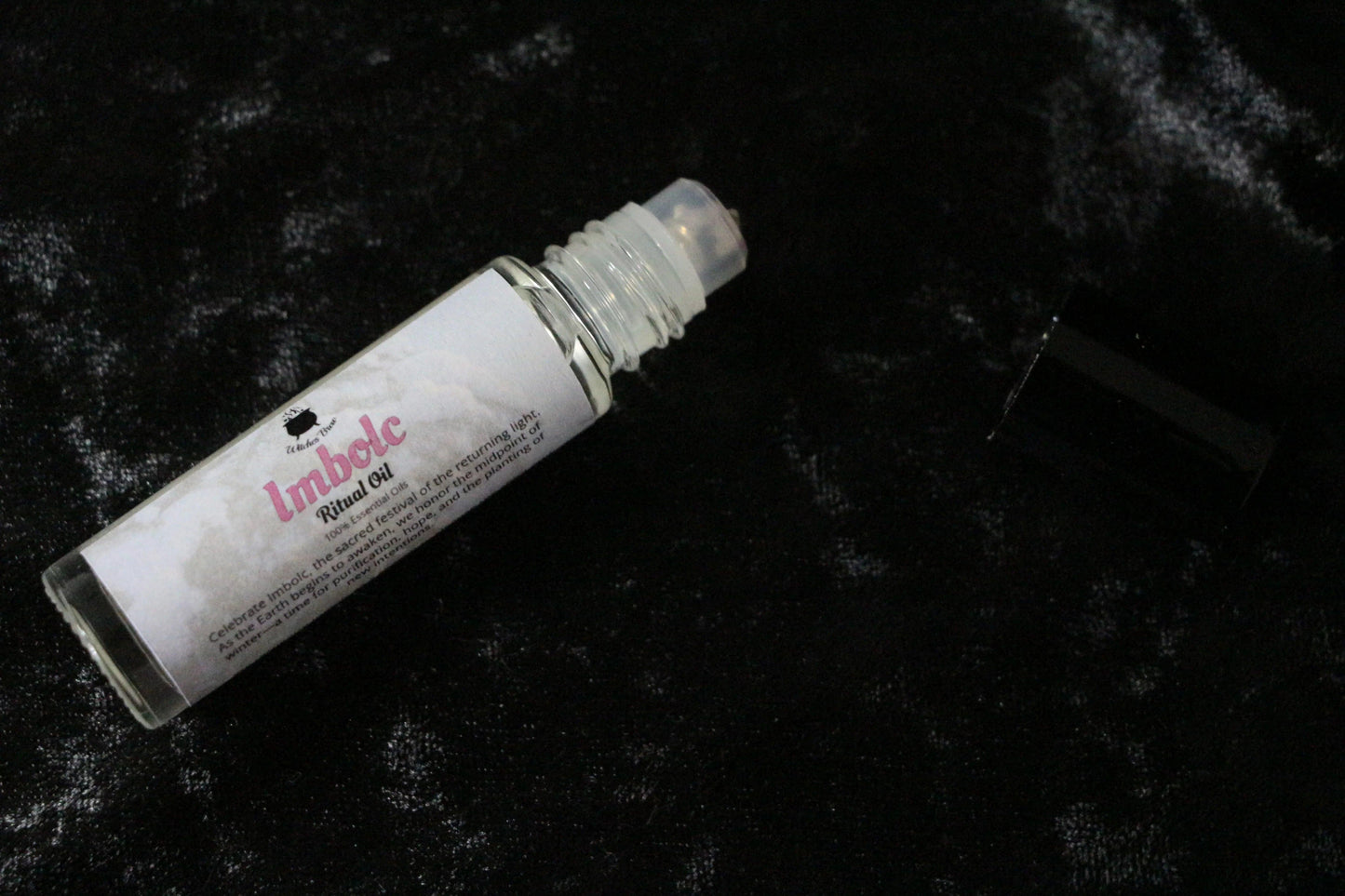Imbolc ritual oil roll-on bottle on black velvet background