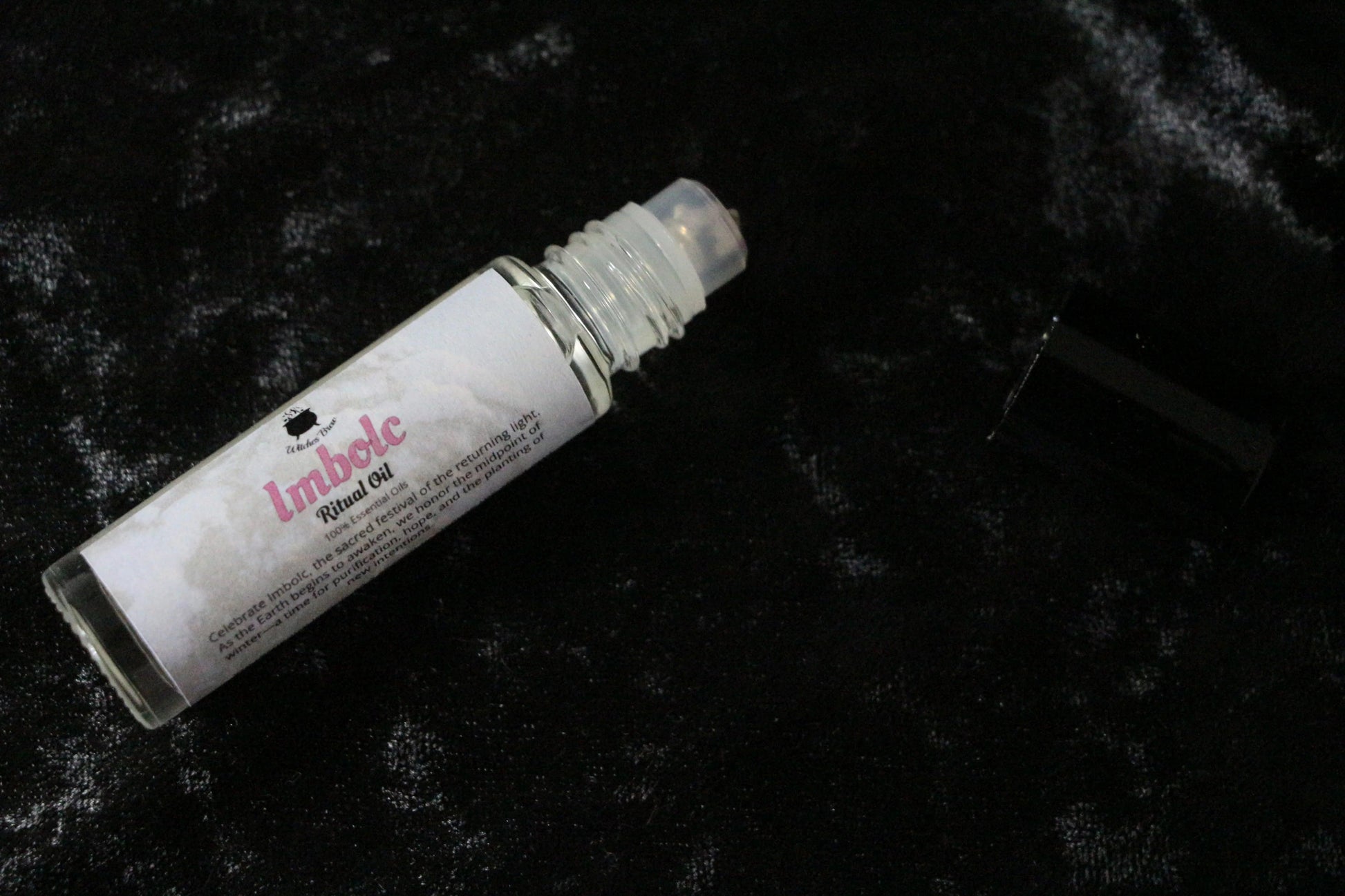 Imbolc ritual oil roll-on bottle on black velvet background