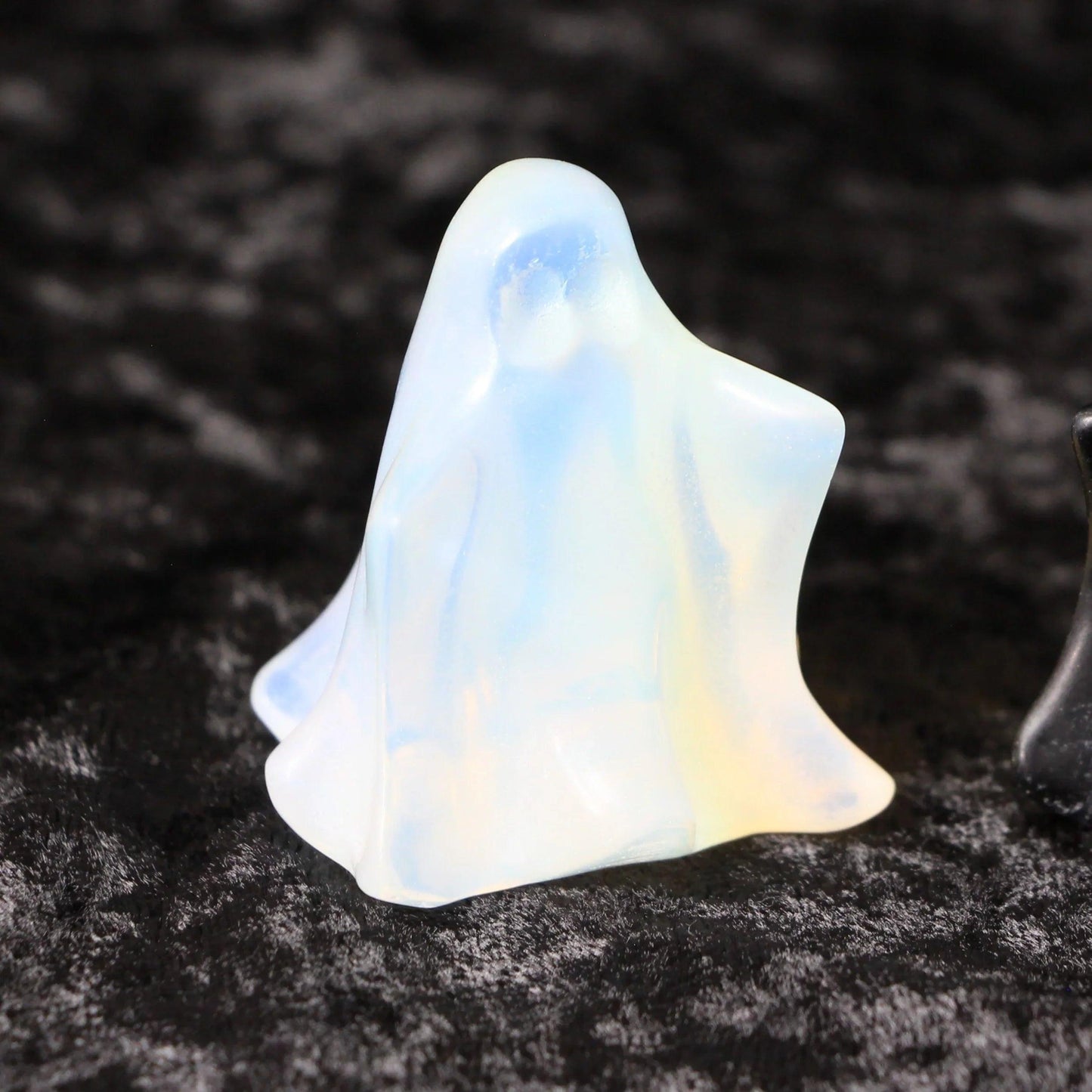 Opalite crystal ghost figurine on black velvet background, witchcraft decor