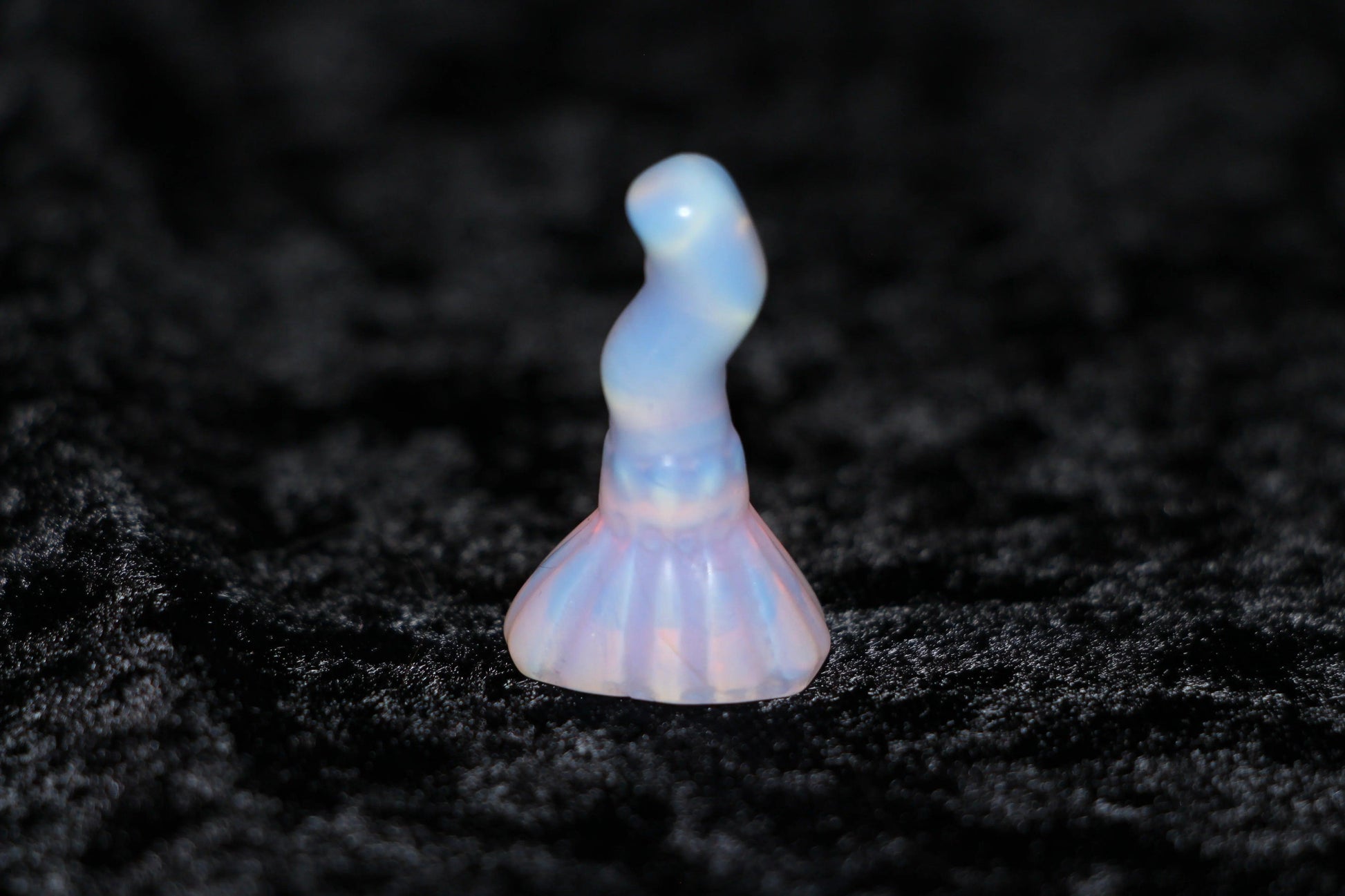Pink opalite crystal figurine for witchcraft rituals on black velvet background