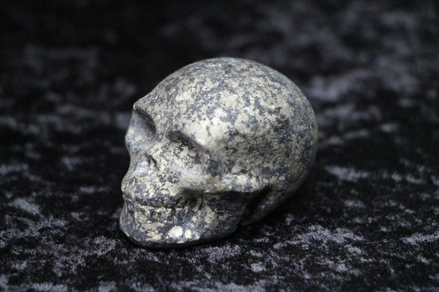 Pyrite crystal skull carving on a dark textured background
