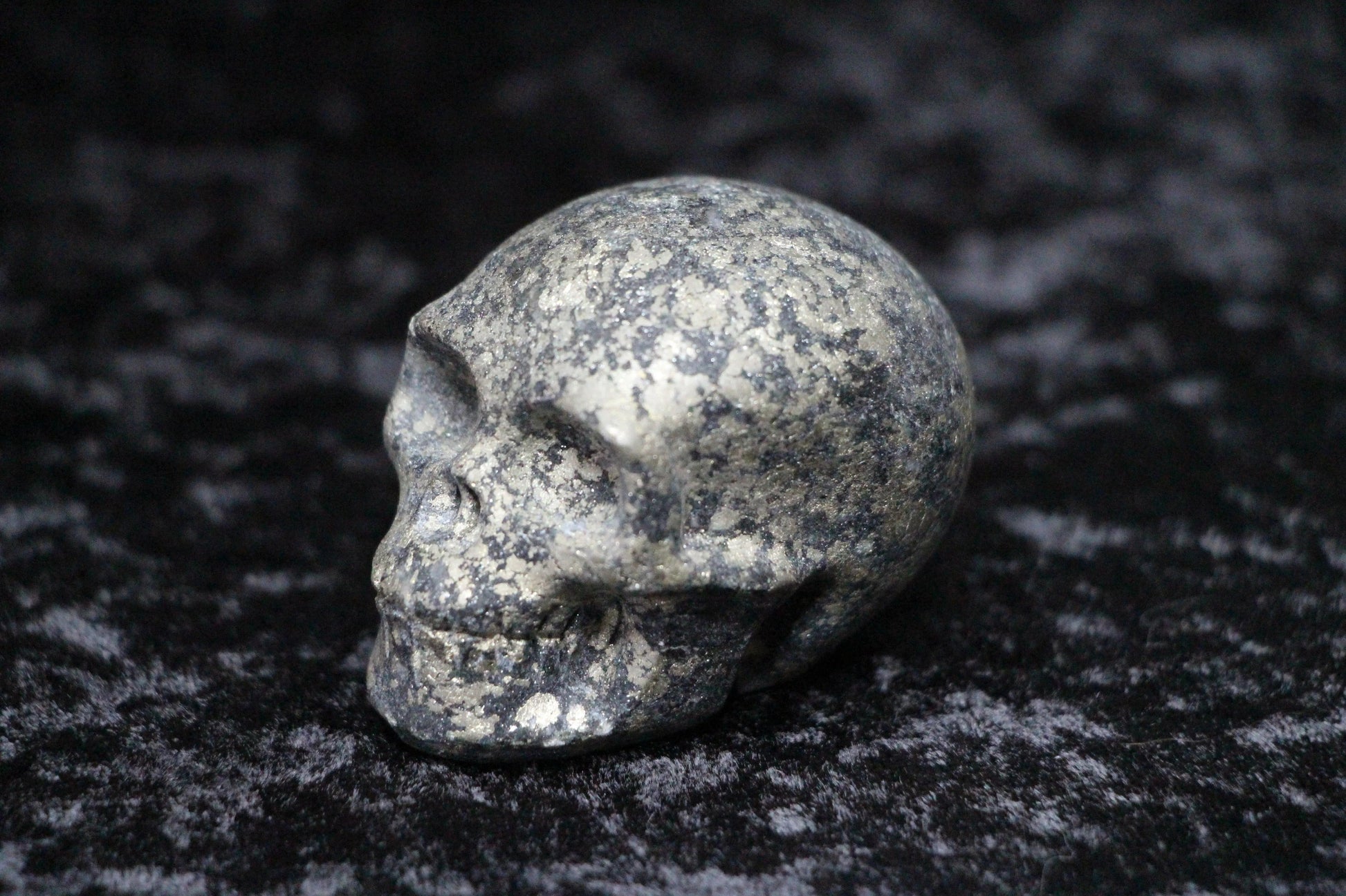 Pyrite crystal skull carving on a dark textured background