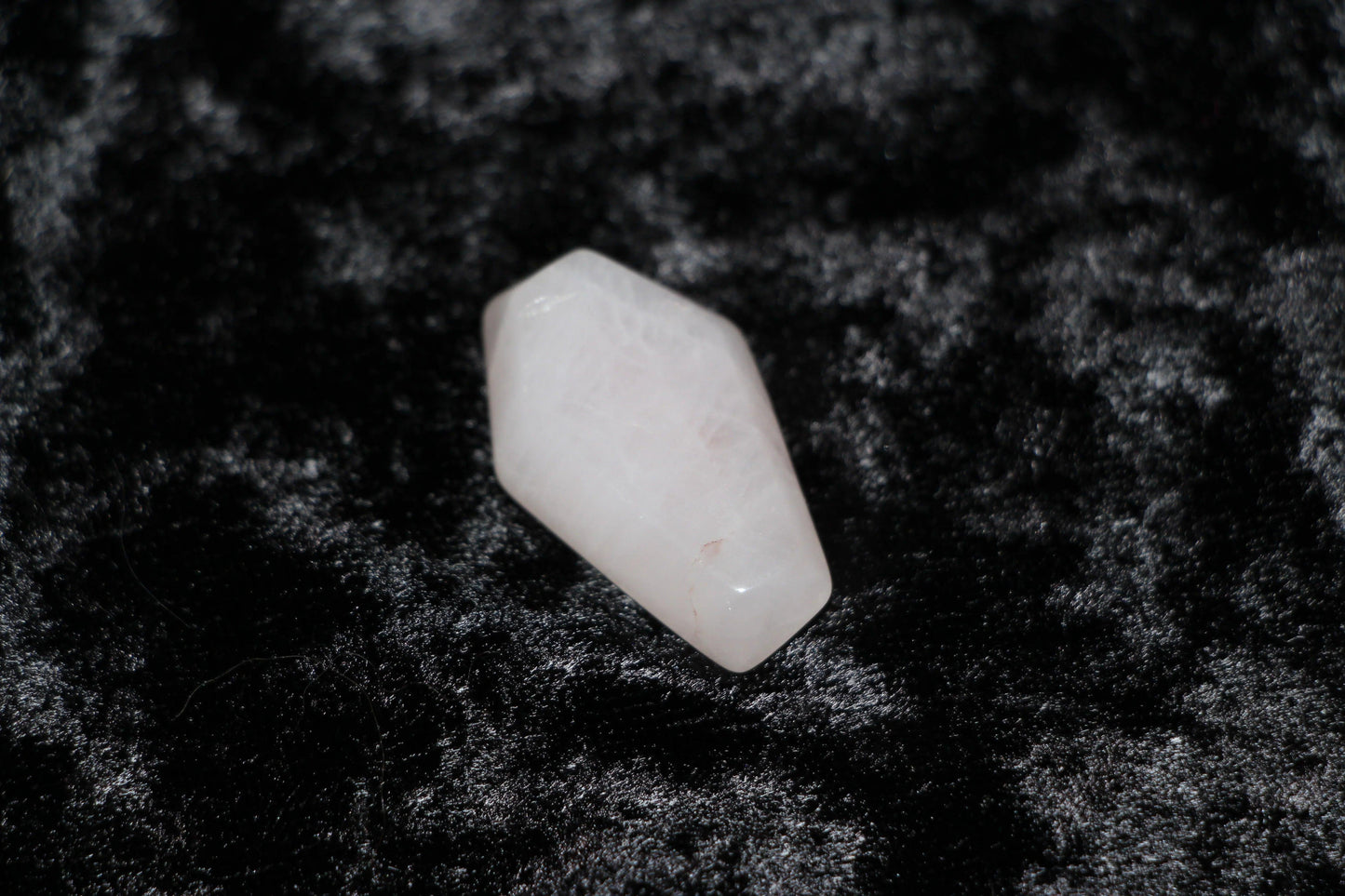 Polished rose quartz crystal on black velvet, ritual tool for modern witch intentions