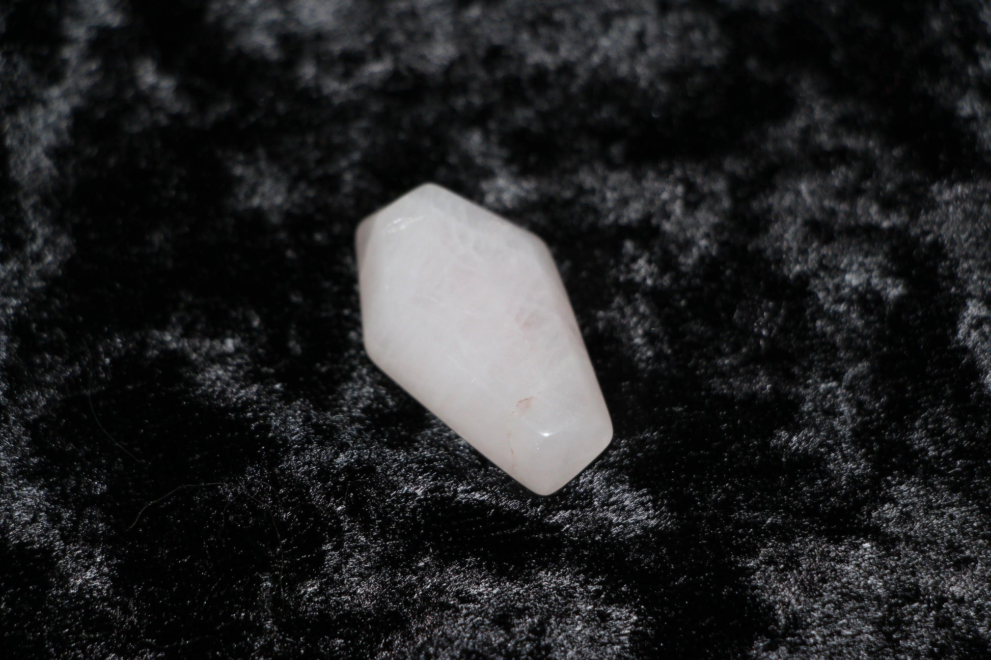 Polished rose quartz crystal on black velvet, ritual tool for modern witch intentions
