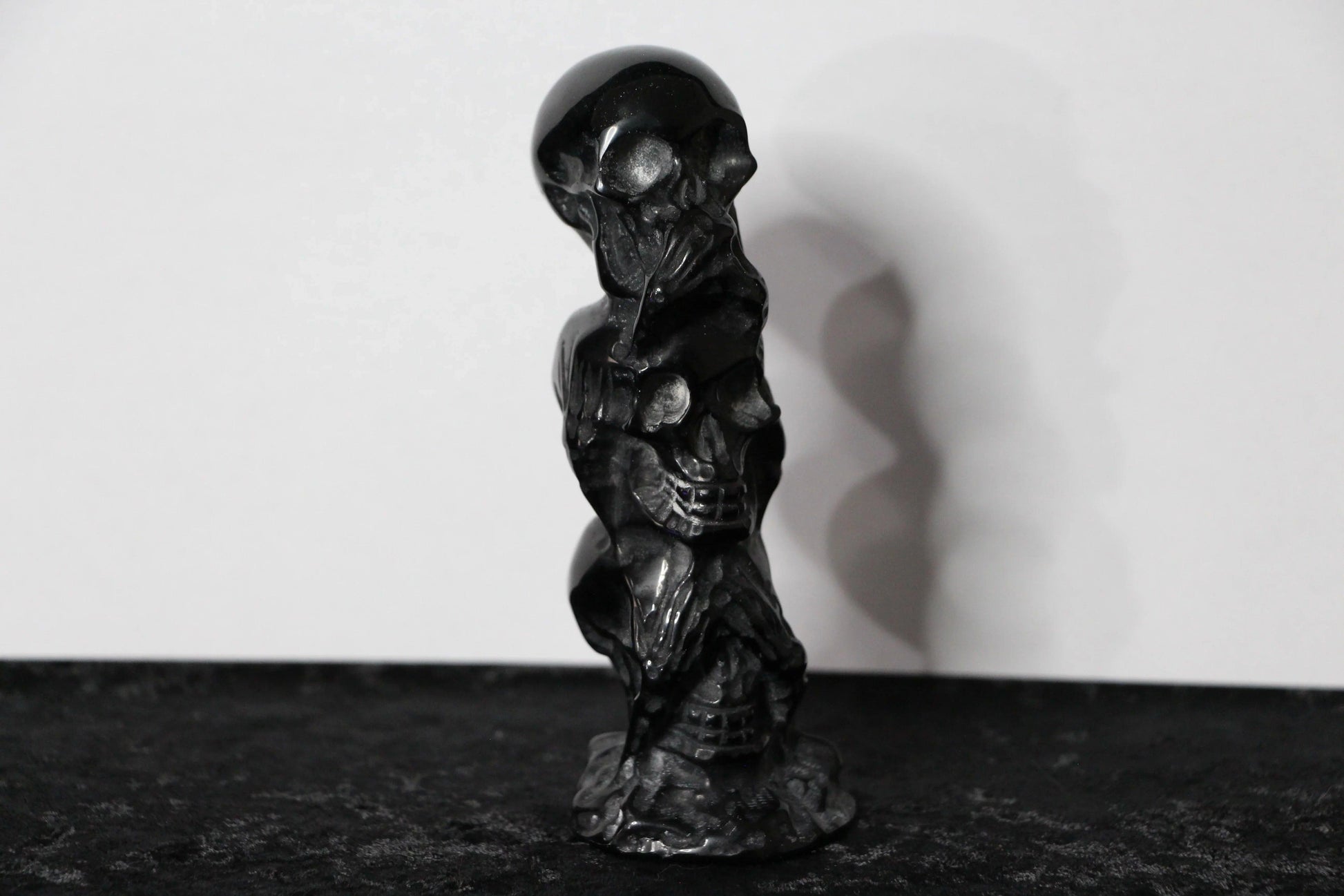 Hand-carved black obsidian skull statue on black surface, modern witch altar decor