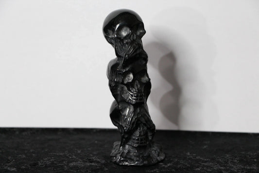 Hand-carved black obsidian skull statue on black surface, modern witch altar decor