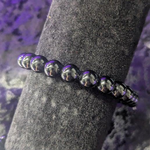 Obsidian crystal bead bracelet on black velvet display with purple background