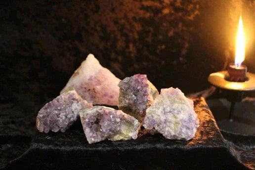 Raw amethyst crystals on velvet with lit candle, mystical altar decor