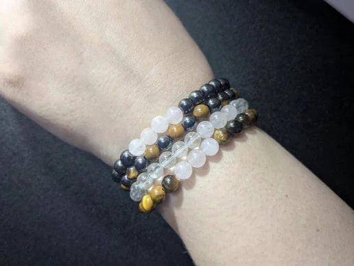 Stacked crystal bead bracelets with black, white, and tiger’s eye stones on wrist