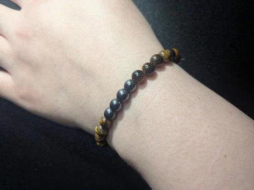 Hand wearing a crystal bead bracelet on a dark background, gemstone jewelry for rituals