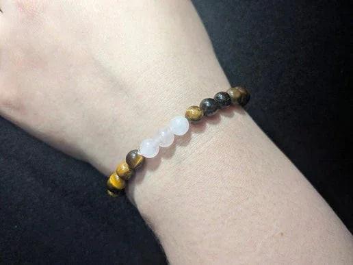 Hand wearing crystal bead bracelet with tiger's eye and rose quartz, ritual jewelry