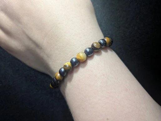 Hand wearing a tiger's eye crystal bead bracelet on black background
